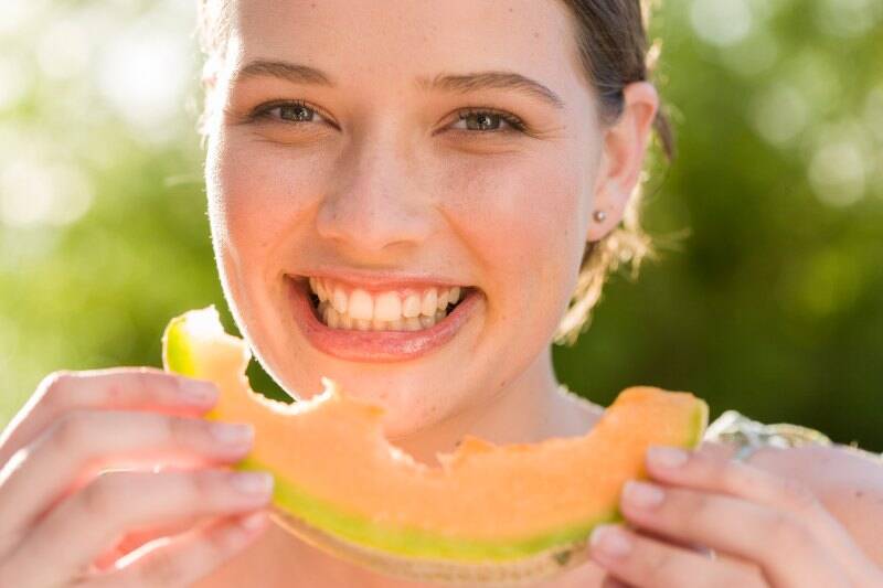 portrait-smiling-woman-eating-melon-outdoors portrait-smiling-woman-eating-melon-outdoors